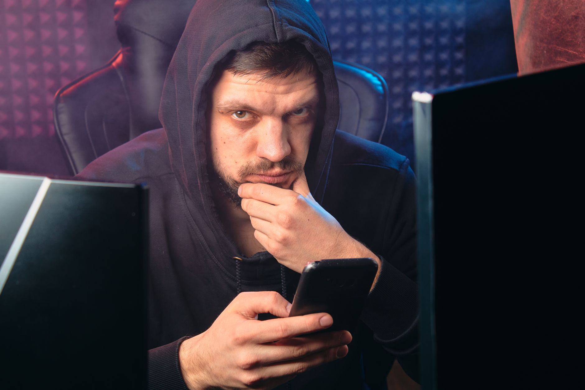 Hooded figure at computer representing a phishing or cybercrime operation
