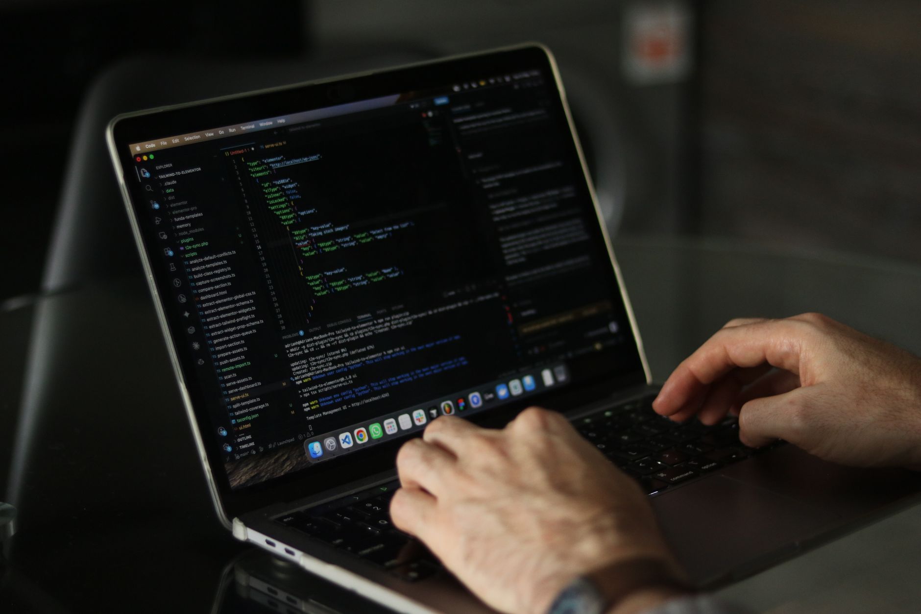 Software developer writing code on a laptop with multiple screens